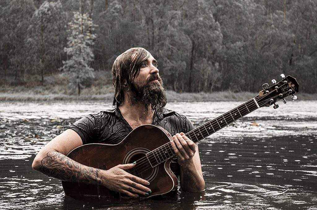 Daryl James with guitar in a lake