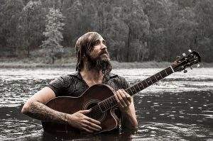 Daryl James with guitar in a lake